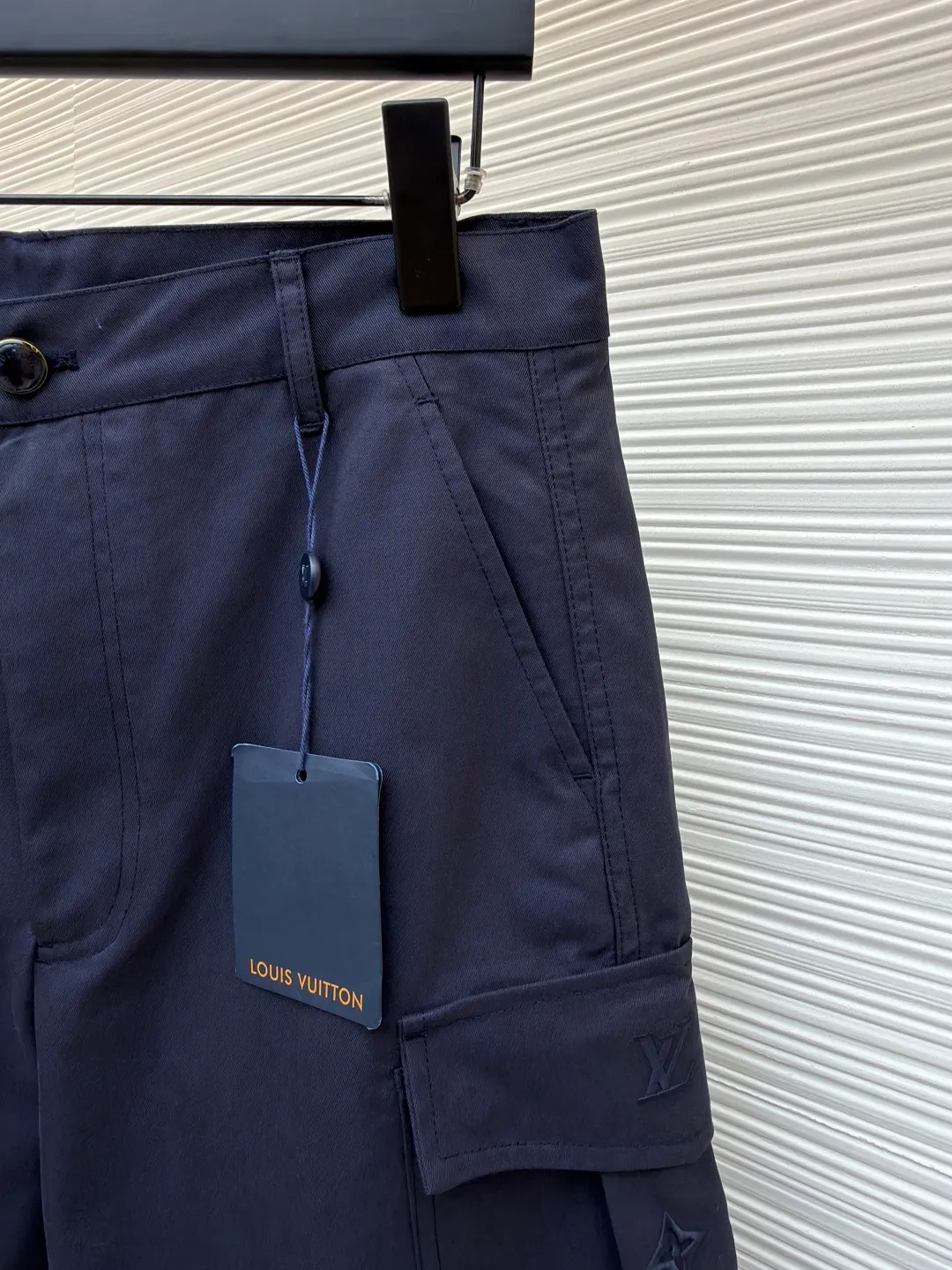 LOUIS VUITTON pocket embroidered work trousers ●Original version: Purchased and developed for 9999 ●Item number: 1681825-B50 ●Fabric: cotton twill fabric ●Technology: embroidery production ●Color: navy blue ●Version: fitted version ●Weight: about 520 grams ●Size: 44-46-48-50 ●Description: The high cotton content ensures the fabric's excellent breathability, durability and classic workwear texture, while the twill weave gives it unique wear resistance and stiffness. The special fabric technology solves the pain points of tight and stiff traditional overalls; it provides greater freedom when moving, significantly improves wearing comfort and flexibility, and achieves a balance between function and comfort. The application of three-dimensional core-spinning embroidery technology in the pocket position is achieved by adding additional cotton thread or foam as the core material to the pattern filling layer, and then using embroidery thread to fully cover the embroidery. The logo pattern is significantly protruded from the surface of the fabric, forming a full three-dimensional effect. This process not only enhances the visual impact and tactile level, but also improves the wear resistance of the pocket area through the buffering effect of the core material, ensuring that the pattern can still remain crisp and not deformed in complex daily use, ensuring that the pattern is clear and durable, and injecting a sense of sophistication into the rugged workwear style. Diversified pocket system combines workwear functionality with sophistication. The flap cargo pockets on both sides are a signature element, and their flap design prevents items from falling and enhances the visual three-dimensionality. Italian style pockets provide simple side storage. The overall wiring is straight and delicate, the fabric is comfortable and soft, and the color is consistent without color difference. It can be matched with the same style to create a fashionable look and control various occasions. Customized accessories, complete with three standards, same style for men and women!
